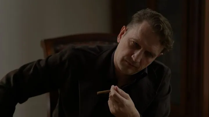 A man with a cigarillo in the manor study