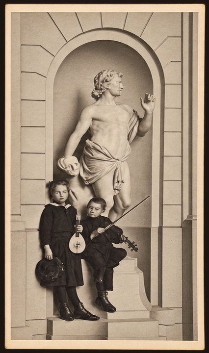 Postcard No. 27 — two children with a mandolin and a violin by the statue of Apollo in a niche, portrait, sepia